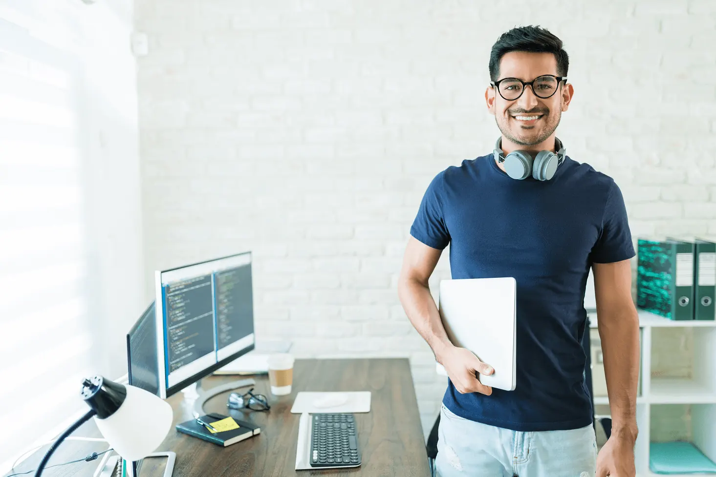 Desenvolvedor trabalhando em home office diante de monitores